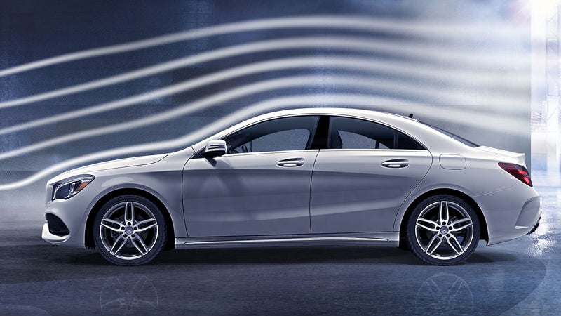 Silver luxury sedan shown in side profile against an abstract background with flowing white lines