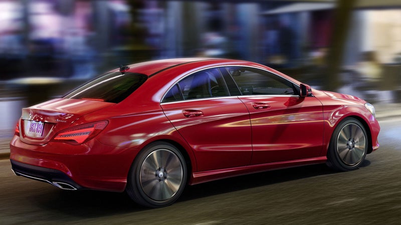 Red luxury sedan driving through a city street with motion blur in the background