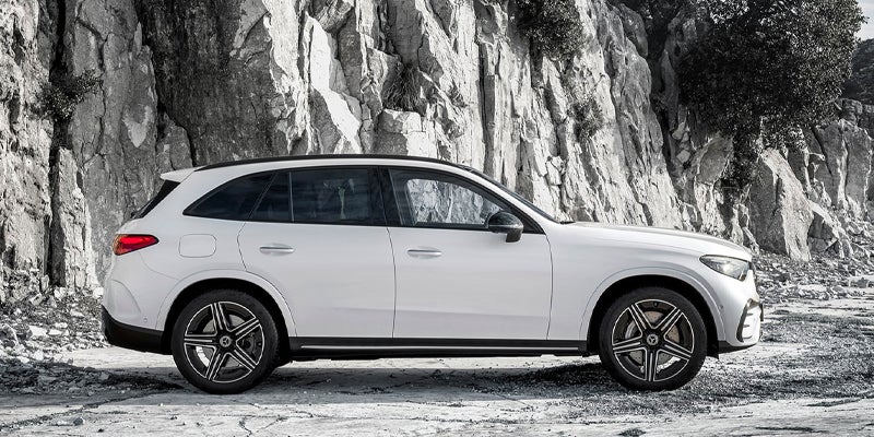 Side profile of a white Mercedes-Benz SUV parked beside a rocky cliff landscape