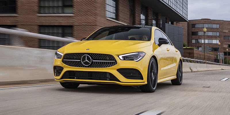 Yellow Mercedes-Benz sedan driving through an urban area with modern buildings in the background