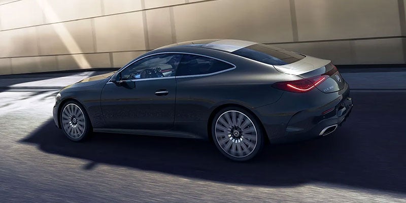 Dark grey Mercedes-Benz CLA 300 coupe with two light silver stripes on the roof and trunk, driving on a road
