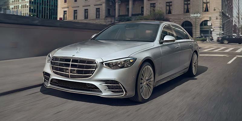 Front three-quarter view of a silver Mercedes-Benz S-Class luxury sedan traveling in an urban setting