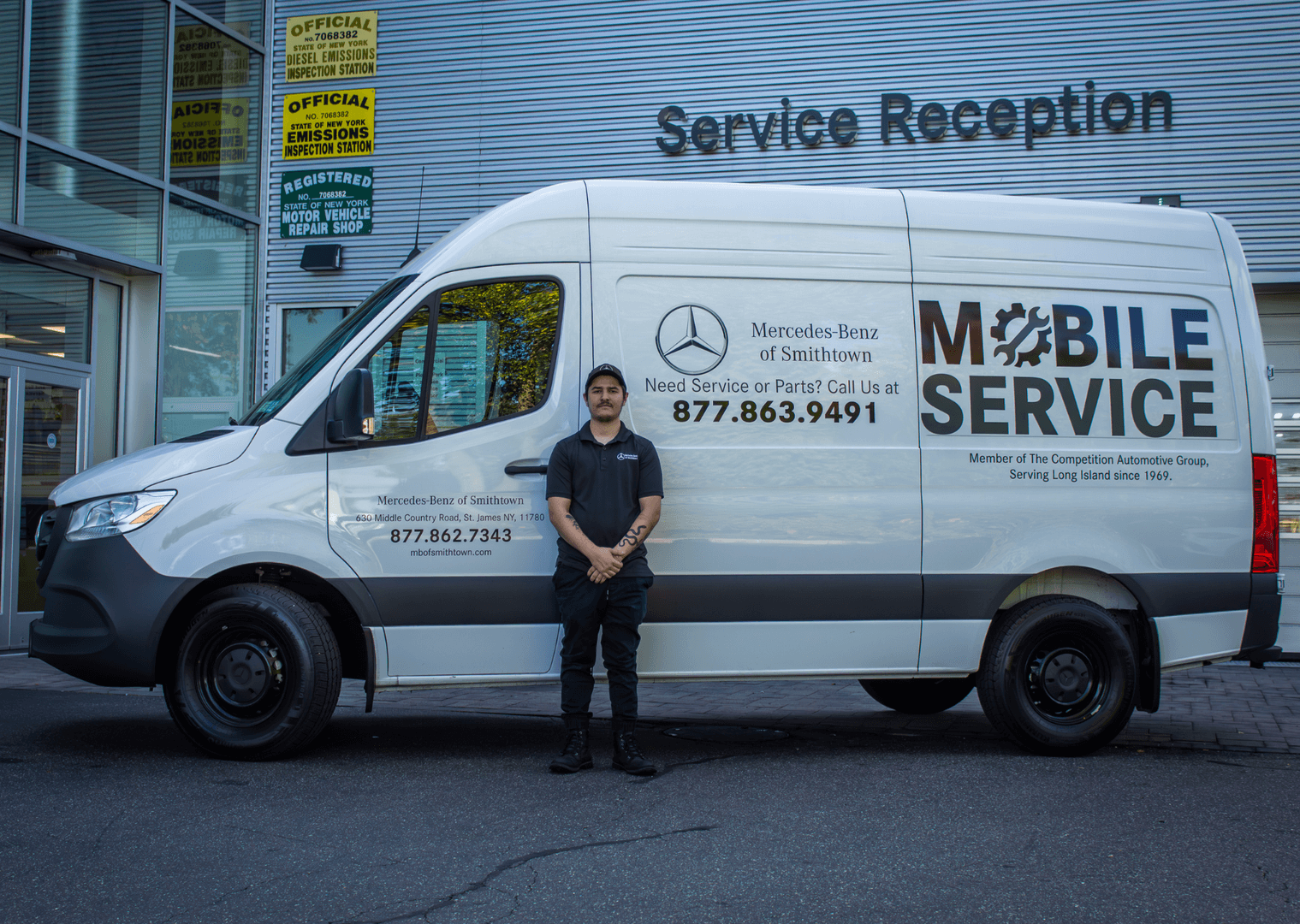 Technician standing by a Mercedes-Benz Mobile Service van outside a service reception area.