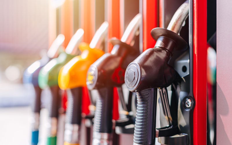 A row of colorful gas pump nozzles, with the closest one being black at a gas station