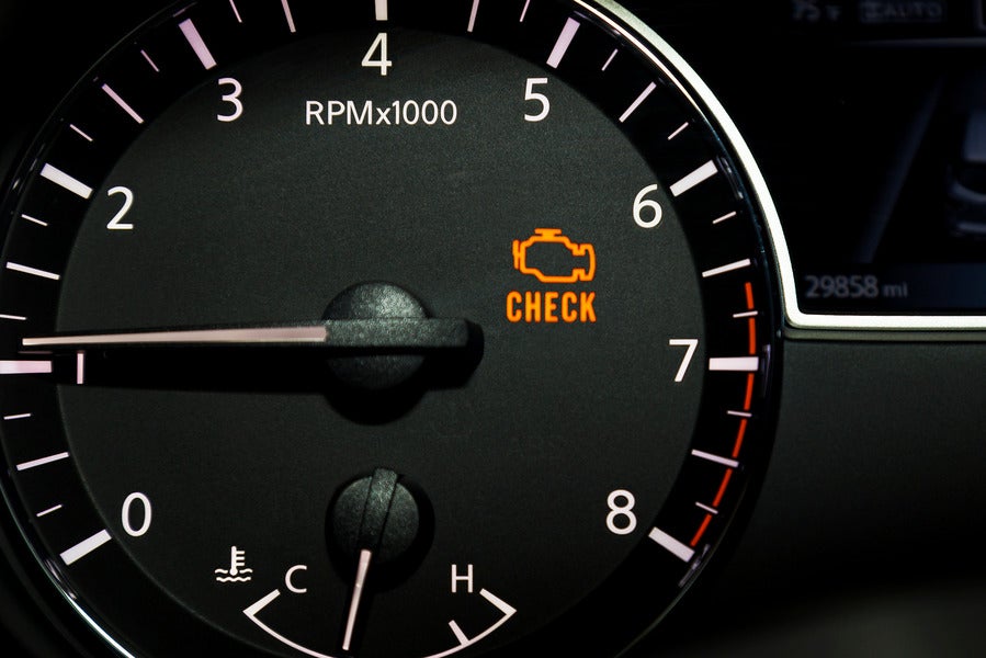 An orange check engine light illuminating the RPM gauge and part of the odometer in a car