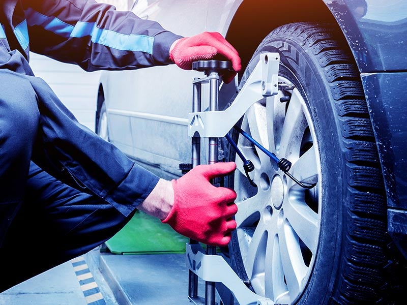 Technician performing a wheel alignment on a vehicle