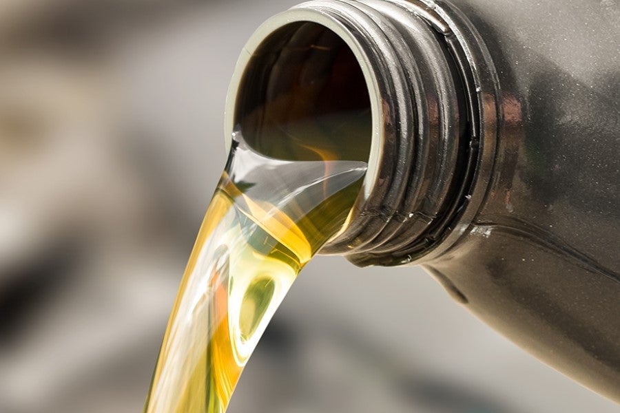 Close-up of clean motor oil being poured from a container during a vehicle engine oil change service