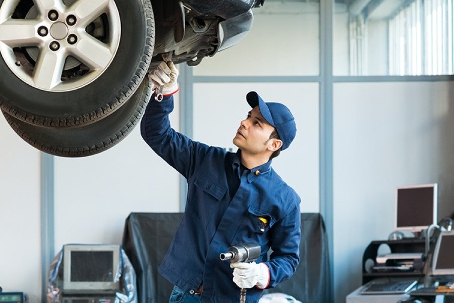 Factory-trained technician inspecting a wheel on a lifted vehicle